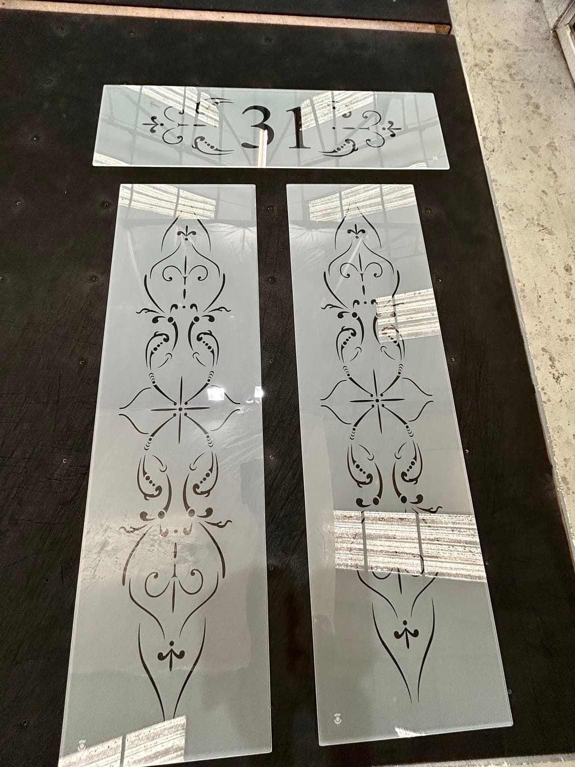 Matching floral door panels and a number 31 fanlight laid out together on the bench